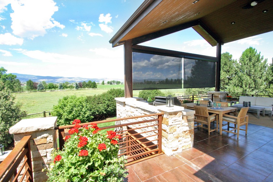 Outdoor roller shade on a patio in Bountiful, Utah, providing shade and views of the surrounding landscape with mountains in the distance.