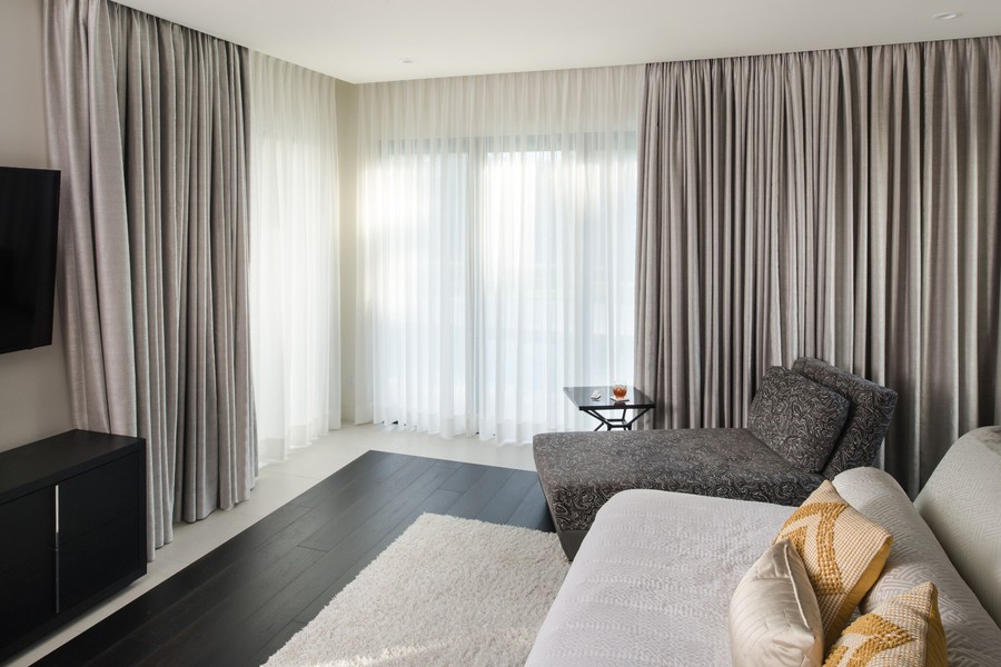 Elegant Lutron sheer and gray fabric motorized drapes pictured in a Bountiful home. 