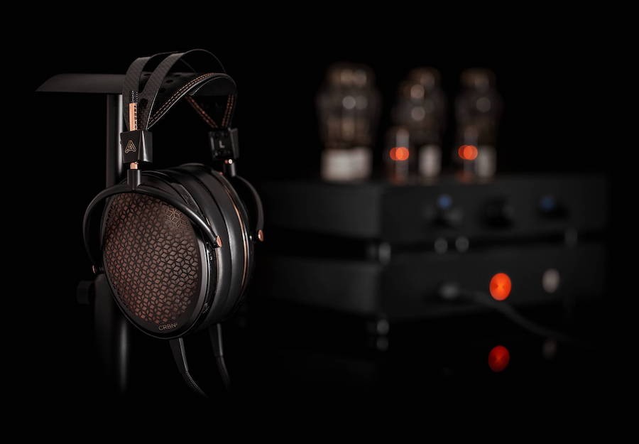 The Audexe CRBN flagship headphone is in the foreground with audio components set in the dark background. 