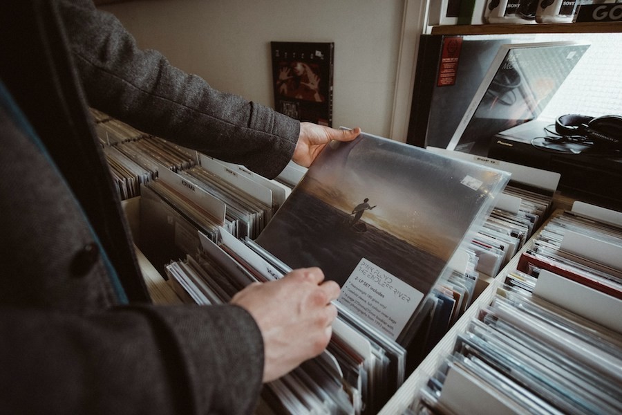 A man looking at a vinyl record album in a music store. 