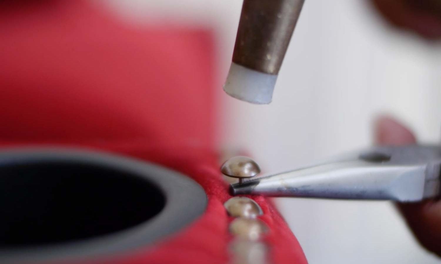 a pinhead being carefully hammered into a red armchair